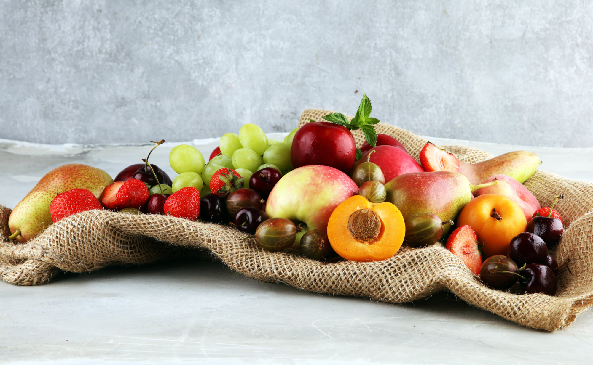 Ein Arrengement aus frischen, farbenfrohen Früchte wie Erdbeeren, Kirschen, Birnen, Äpfel, Aprikosen und Stachelbeeren, das symbolisch für die Kraft der Antioxidantien in Pflanzen steht.